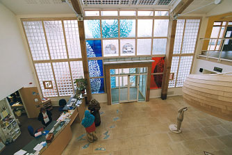General view of foyer with reception desk and staircase by Walter Jack Studio, floor by Marion Brandis, window by Anne Smyth and sculpture, Reg, by Lucy Casson, 2004.  Wellspring Healthy Living Centre, Barton Hill, Bristol.